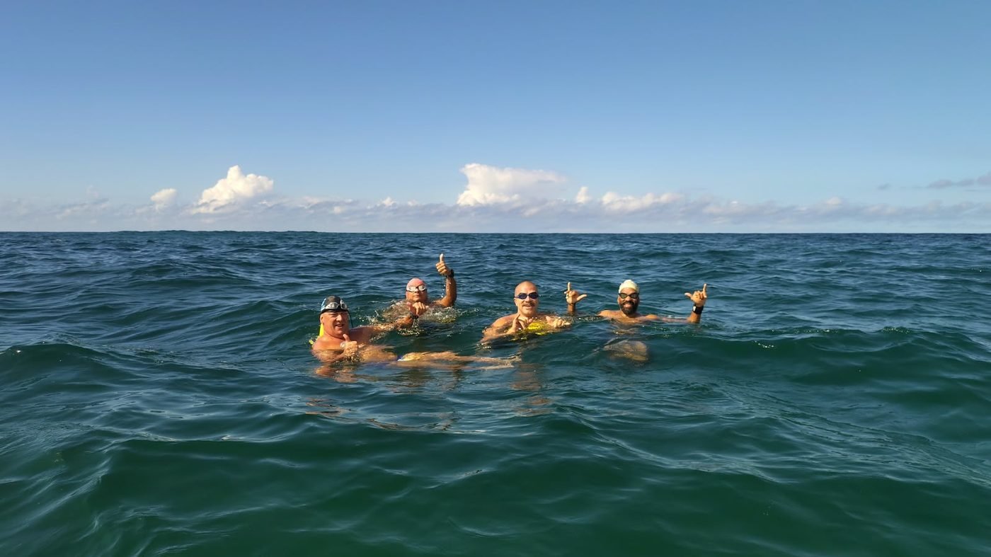Alunos nadando em mar aberto com boias de sinalização